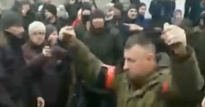 Russian soldier holds grenades in air as he walks among Ukrainians demanding surrender