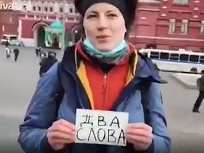 Russian protester holds up sign saying ‘two words’ and is marched away by armed police seconds later