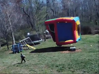 Video shows jumping castle going airborne in strong wind and narrowly missing children