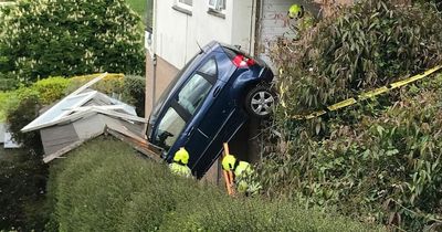 Driver's miraculous escape after car smashes through wall and hangs over 10ft drop