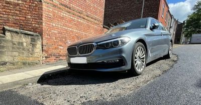 Workers resurface road around parked BMW