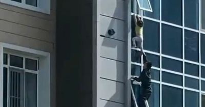 Hero saves girl, 3, from 100ft drop by catching her as she dangles from window