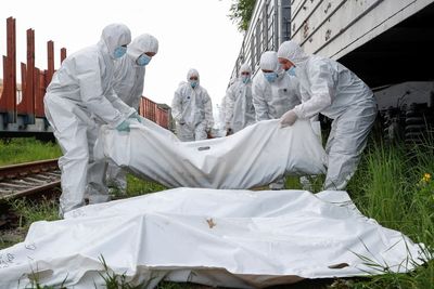 Ukrainian servicemen load bodies of Russian soldiers onto refrigerated rail cars