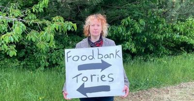 Mum protests outside Welsh Tory conference holding a sign pointing to a food bank