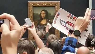 Man disguised as old woman throws cake at glass protecting the Mona Lisa painting