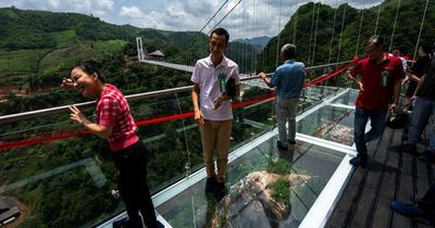 Fearless tourists take on world's longest glass-bottomed bridge as it claims new record