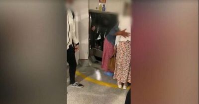 Moment Manchester Airport passengers climb through baggage carousel to get luggage