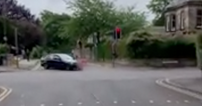 Watch as reckless BMW driver mounts kerb before zooming through red light on Scots street