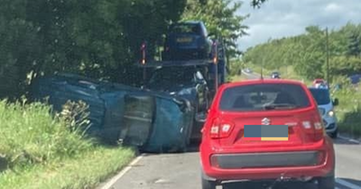 Car falls off the back of transporter partially blocking Scots road