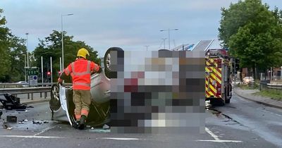 Emergency services scrambled after car flips onto roof in crash on main road