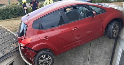 Car hangs 20ft off ground wedged between two buildings after smashing into railings