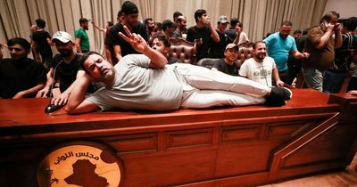 Hundreds storm parliament building with protesters pictured lounging on desks