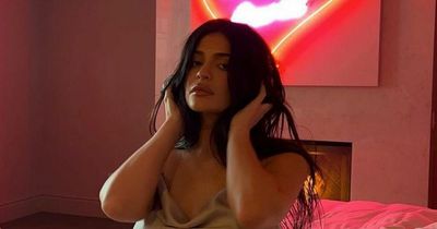 Kylie Jenner shows off leg scar as she poses seductively on a bed in a slinky slip dress