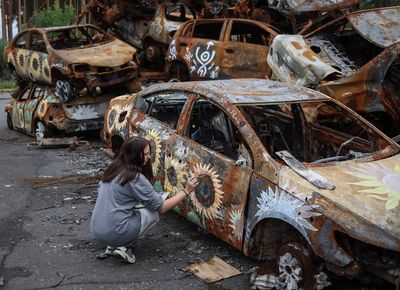 Artists paint flowers over Ukraine war wreckage, unsettling some locals