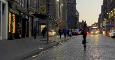 Reckless Edinburgh motorcycle driver climbs atop bike and races along the Royal Mile