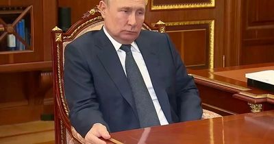 Grimacing Vladimir Putin tightly grips desk in meeting with most trusted general