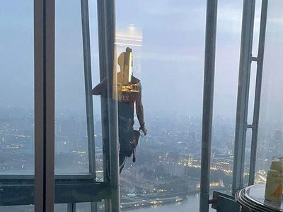 Couple wave at barefoot man climbing past their window at the Shard 40 floors up