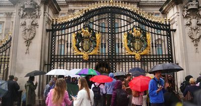 People lay flowers outside Buckingham Palace as crowds gather