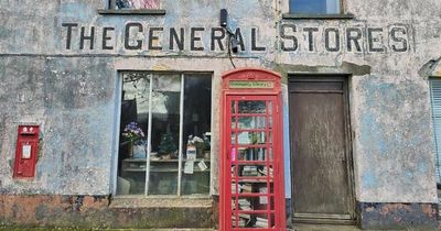 Inside abandoned vintage shop with dusty stock and Grade II red phone box on doorstep