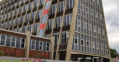 Inside abandoned university building with peeling student posters and decaying walls