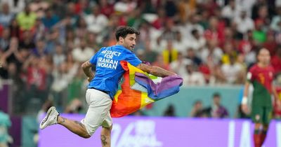 World Cup pitch invader wearing 'Save Ukraine' shirt waves rainbow flag during Portugal vs. Uruguay