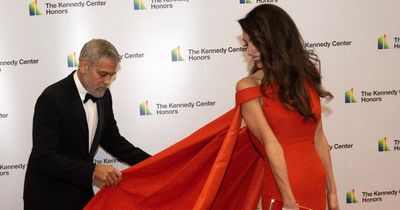 George Clooney sweetly fixes wife's dress train while pair stun on red carpet