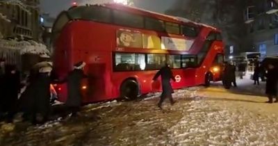 Londoners team up to heave double-decker bus to safety after it's stuck in heavy snow