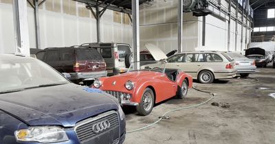Inside abandoned warehouse with car graveyard of Rolls-Royces, Land Rovers and BMWs