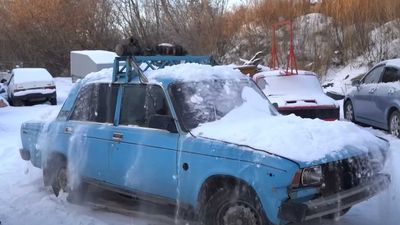 Lada With Unbalanced Crankshaft On Roof Shivers In Cold To Shake Off Snow