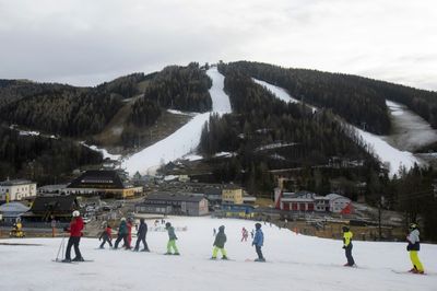 Alpine tourists ski amid brown hillsides