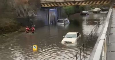 Fire crews wade through floodwater as cars left fully submerged on road