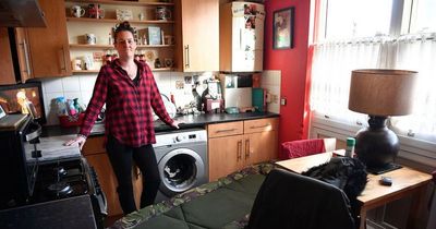 Single mum sleeping on camping bed in kitchen as home is covered in black mould
