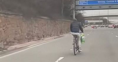 Glasgow cyclist on M8 motorway in jeans and puffer jacket with Asda bag over handlebars