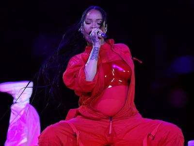 Rihanna wears custom red Loewe jumpsuit as she reveals pregnant baby bump