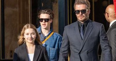 David Beckham holds hands with Harper as family support Victoria at fashion show