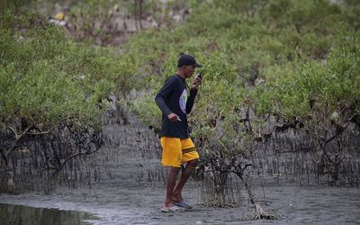 Philippine residents mop up oil spill using only mugs and buckets