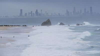 Police search for woman feared swept from rocks in rough conditions on Gold Coast beach
