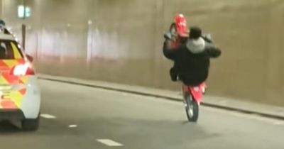 Moment wheelie-pulling biker taunts police on patrol as onlookers accuse force of 'doing nothing'