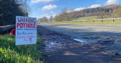 Fuming driver puts up 'swimming pool' sign next to gaping pot hole in road