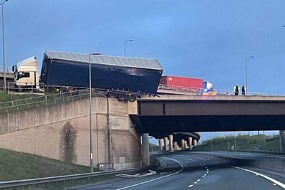 Lorry left hanging above A road after crashing into bridge barrier