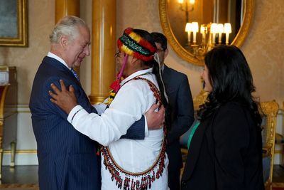 King gets feathered crown and hug ahead of coronation