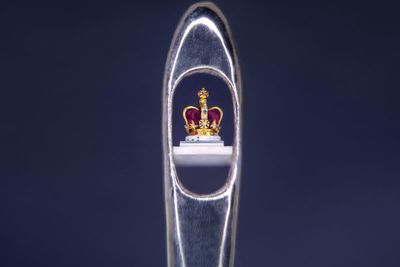 Sculptor creates tiny crown in the eye of a needle as coronation tribute