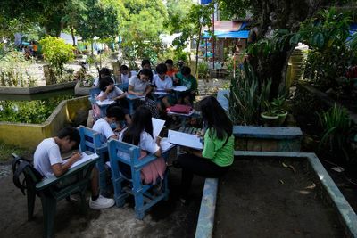 Students meet under trees as schools shelter villagers displaced by Philippine volcano