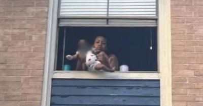 Mum dangles infant son out of 3rd-story window as terrified neighbours gather underneath