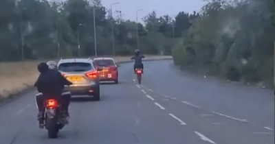 Youth on off-road motorbike seen pulling wheelie past learner on busy Scots road