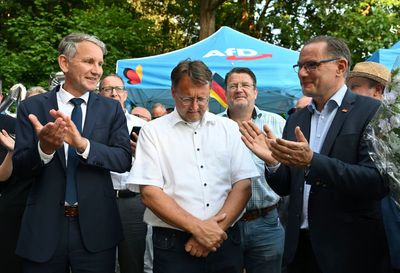 After a far-right victory in German county, a man in neo-Nazi clothing hands balloons to children