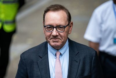 Kevin Spacey smiles and waves as he arrives at court for sex offences trial