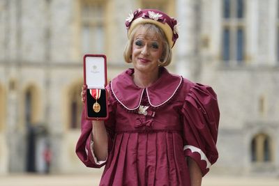 Grayson Perry accepts knighthood in burgundy taffeta dress in honour of the King