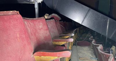 Inside abandoned theatre frozen in time with cigarette machine and sprawling staircase