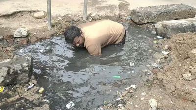 Sanitary worker cleans open drain with bare hands in T.N.; town panchayat officials get show-cause notices